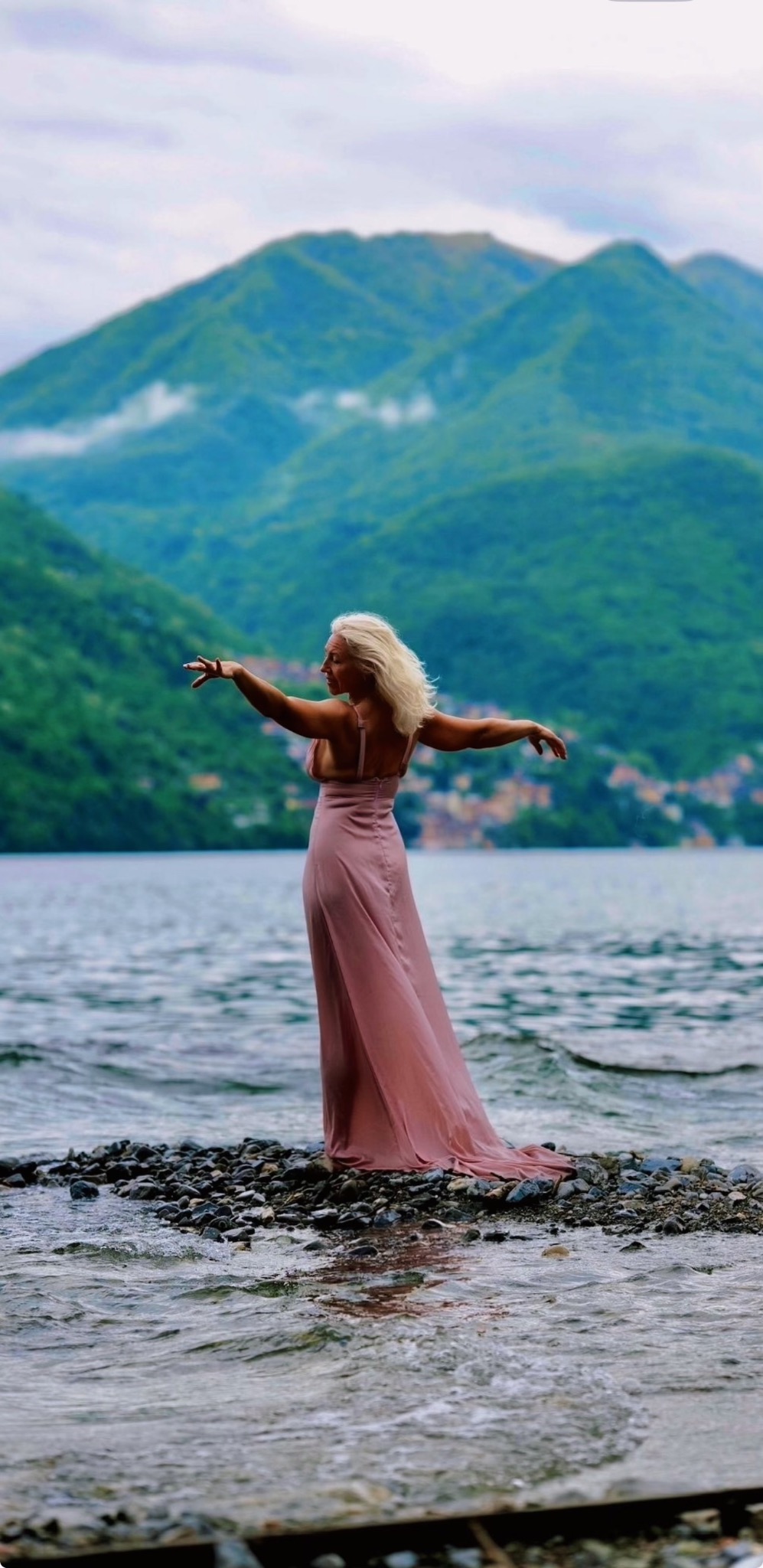 Lina in a flowing dance pose beside a mountain lake