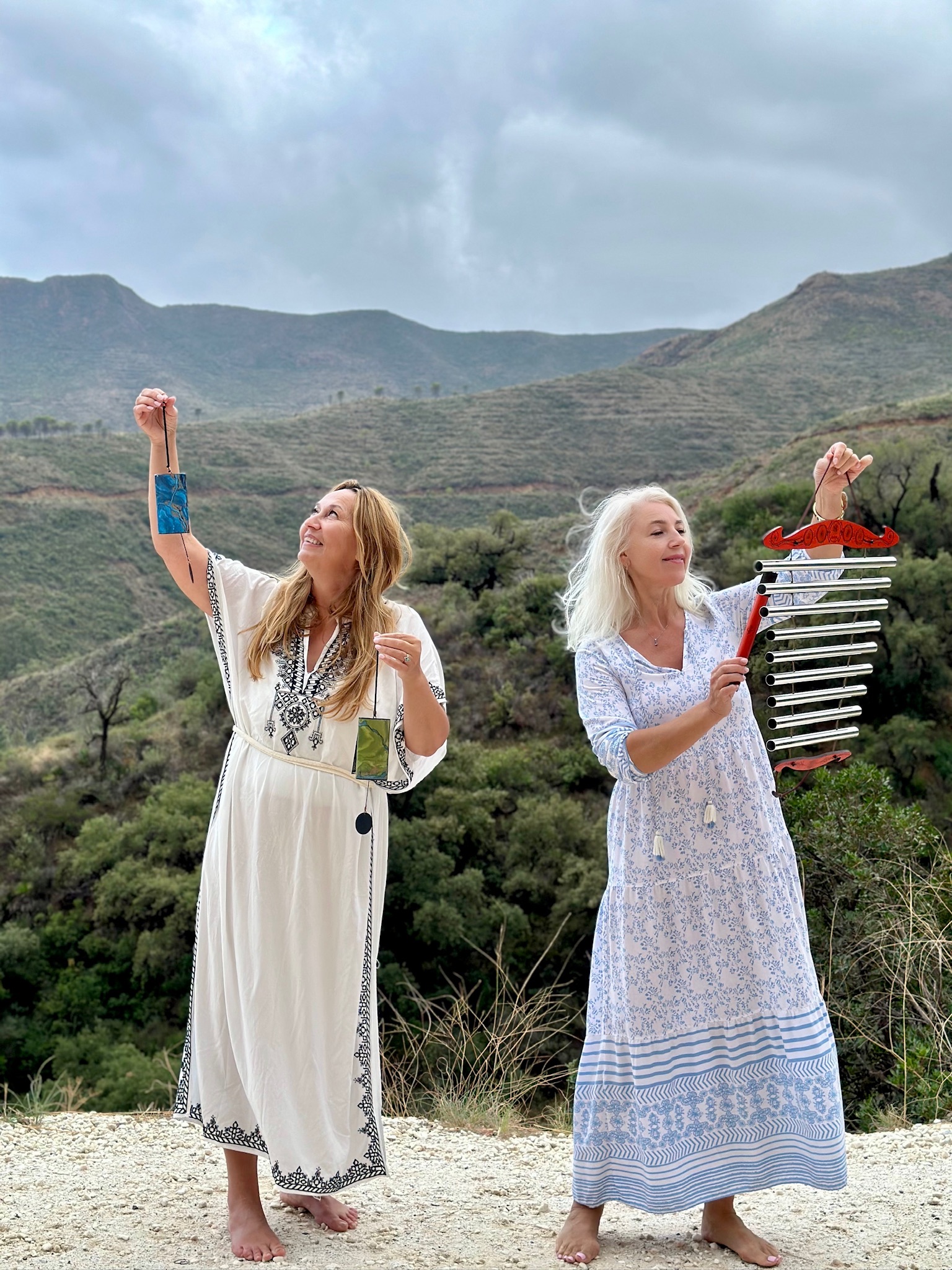 Lina and Axana standing in the mountains with sound-healing instruments